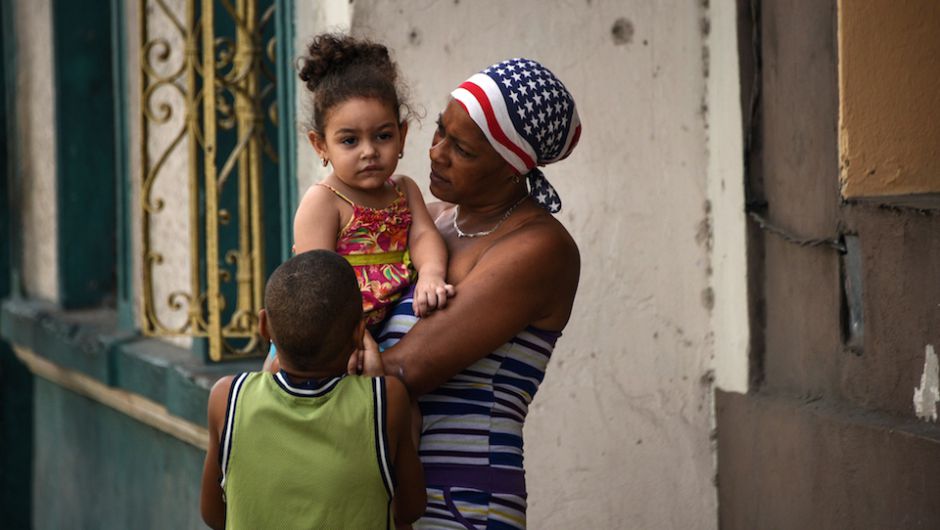 Una mujer con un pañuelo con los colores de la bandera de EE.UU. captada con sus hijos en una calle de La Habana, a unas horas de la llegada del presidente Barack Obama.