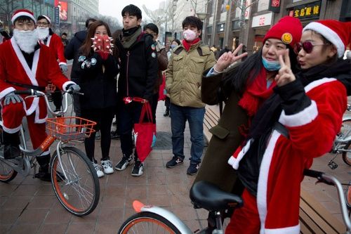 Trabajadores vestidos como Santa Claus promueven el popular servicio de alquiler de bicicletas conocido como Mobike en Beijing, China.