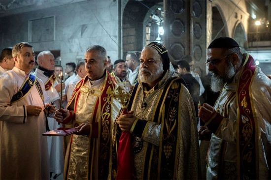 Los sacerdotes dirigen una misa de Navidad en la Iglesia Ortodoxa Asiria de Mart Shmoni, en Bartella, Irak. Unos 300 cristianos se enfrentaron a la lluvia y el viento para asistir a la eucaristía.
