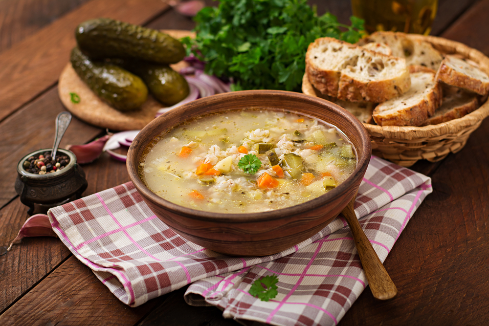 Soup with pickled cucumbers and pearl barley - rassolnik on a wooden background.