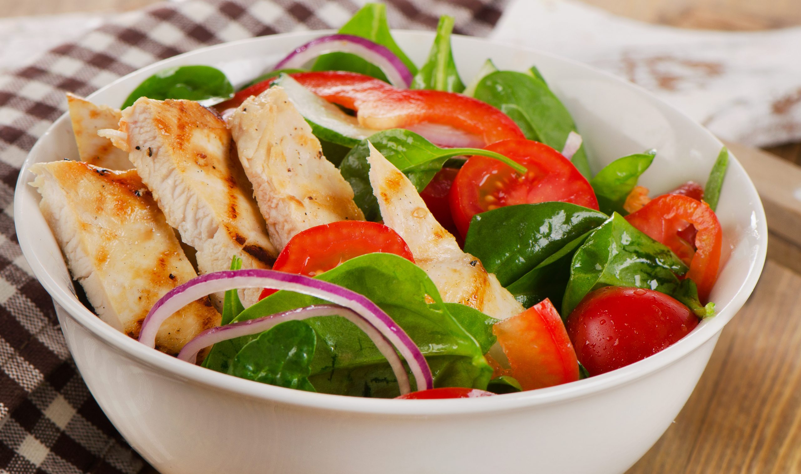 Salad with grilled chicken in bowl.