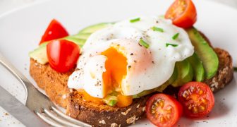 Healthy whole grain bread toast with avocado, poached egg, cherry tomato and baby leaves salad