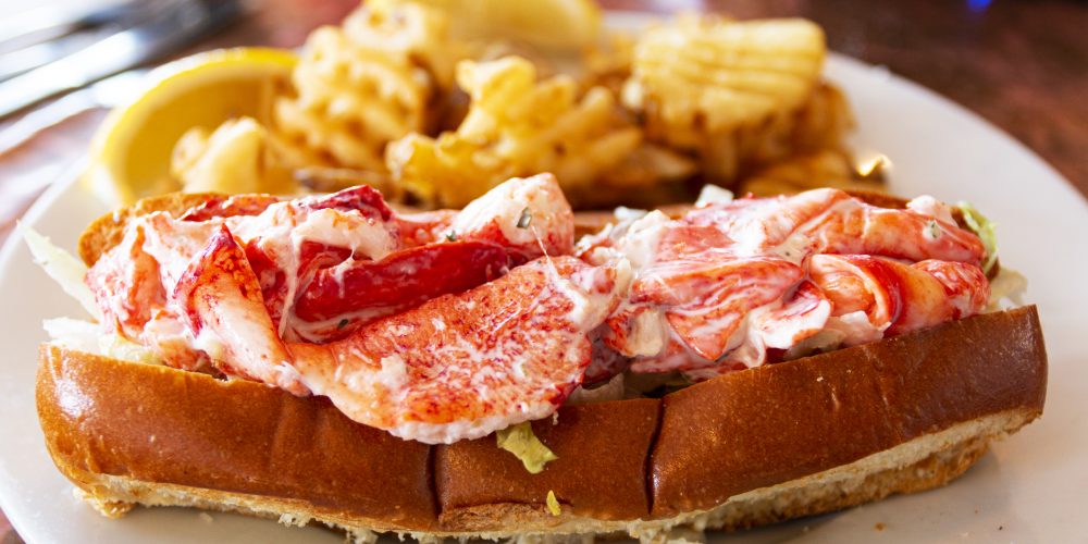 A fresh lobster roll served with waffle fries in a restaurant in Portland Maine.