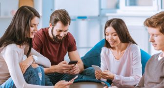 Total digitalization. Merry four friends using gadgets and staring at screens