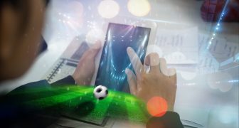Hand hold a phone with betting online on a screen on the background of a stadium.Soccer online concept